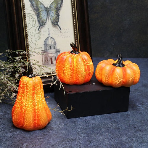 Three lit pumpkin lamps beside a framed print and dried flowers